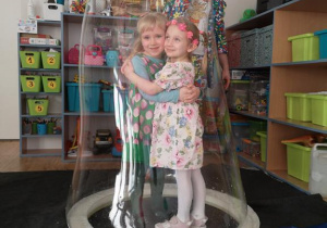 Widok na dwie dziewczynki zamknięte w bańce mydlanej.
